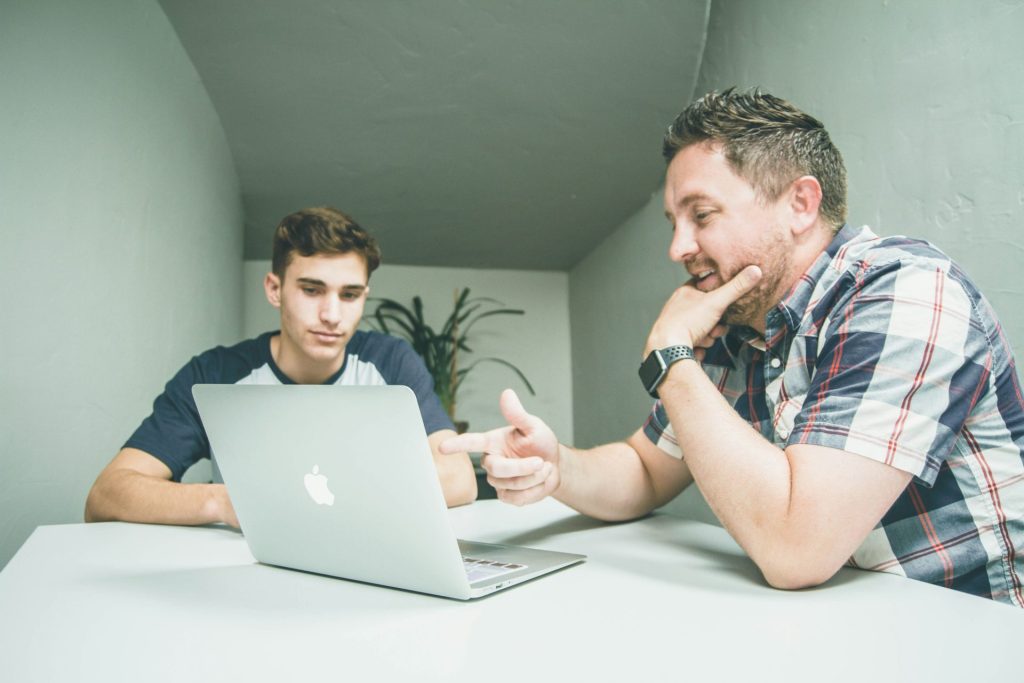 Mentor guiding student on laptop usage